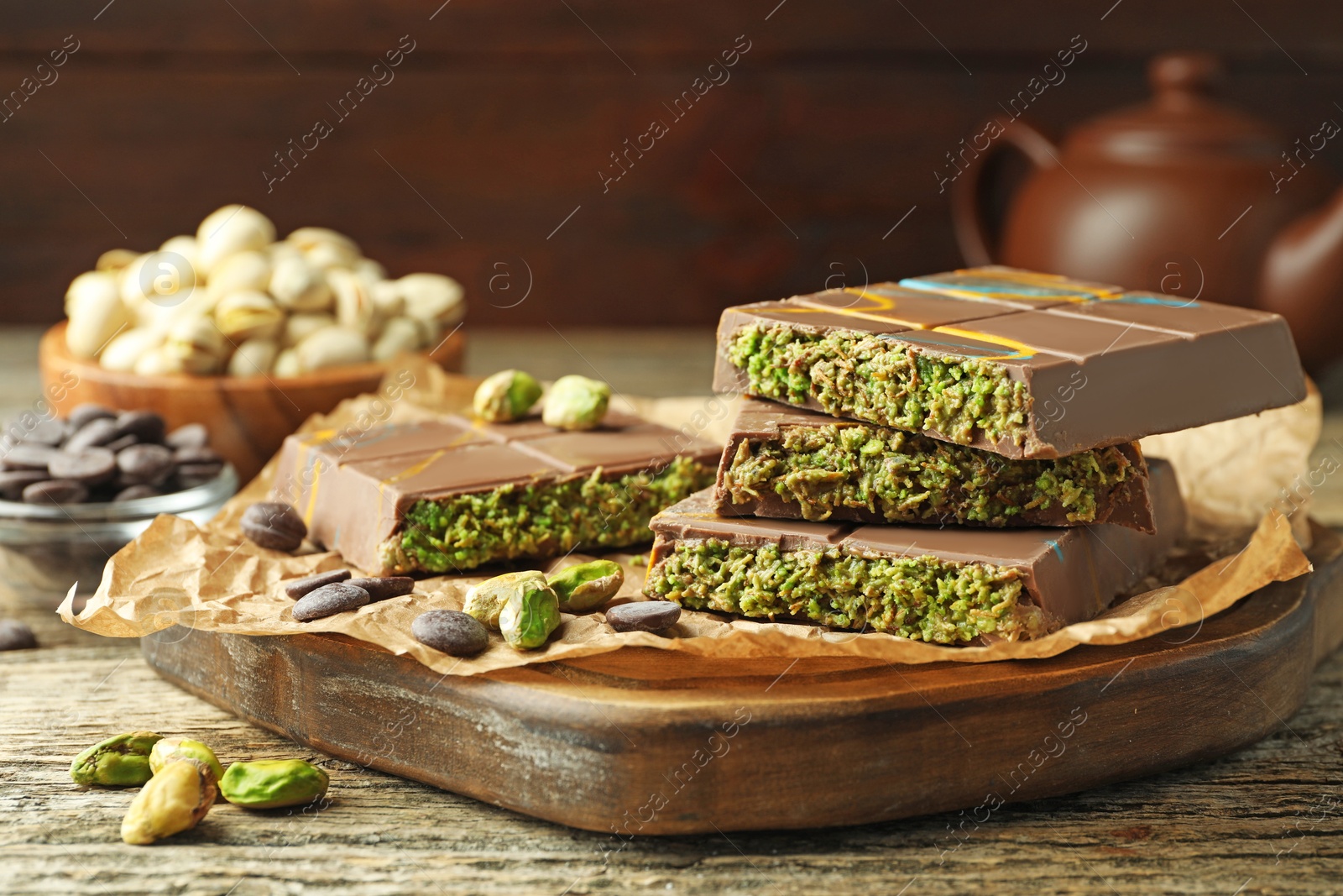 Photo of Pieces of Dubai chocolate bar with pistachios, knafeh and cacao chips on wooden table, closeup