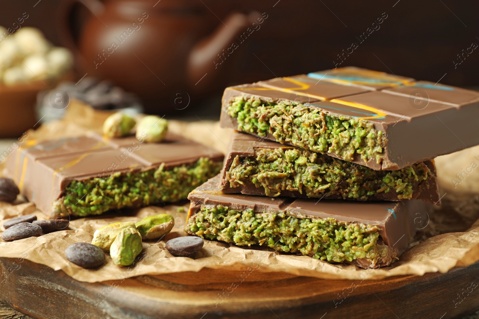 Photo of Pieces of Dubai chocolate bar with pistachios, knafeh and cacao chips on table, closeup