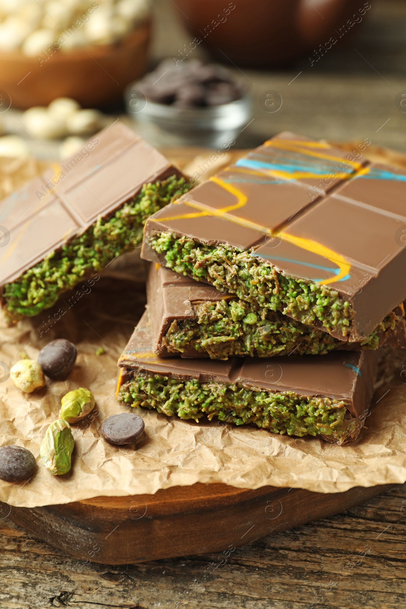 Photo of Pieces of Dubai chocolate bar with pistachios, knafeh and cacao chips on wooden table, closeup