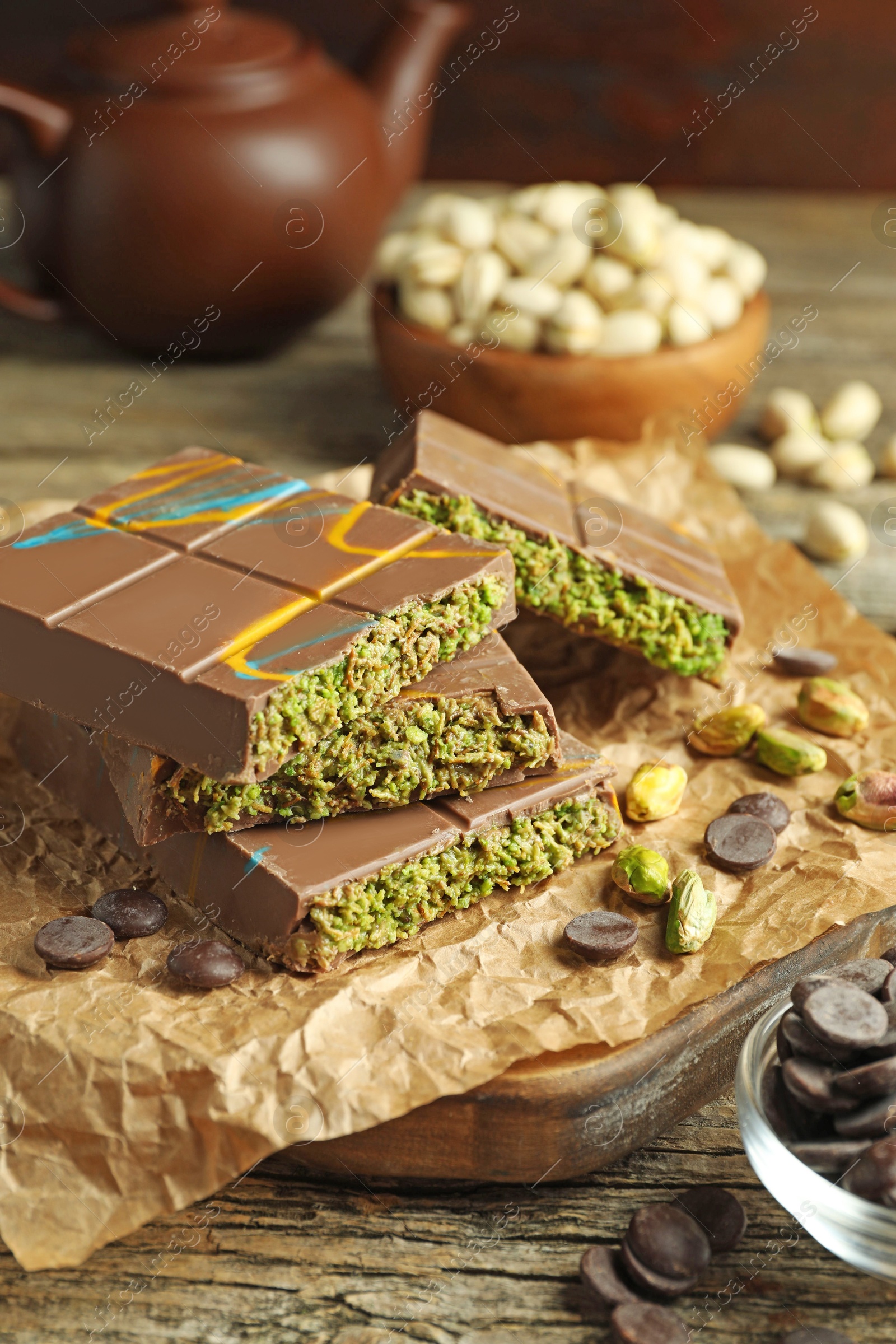 Photo of Pieces of Dubai chocolate bar with pistachios, knafeh and cacao chips on wooden table, closeup