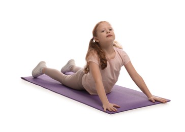 Photo of Cute little girl on fitness mat against white background