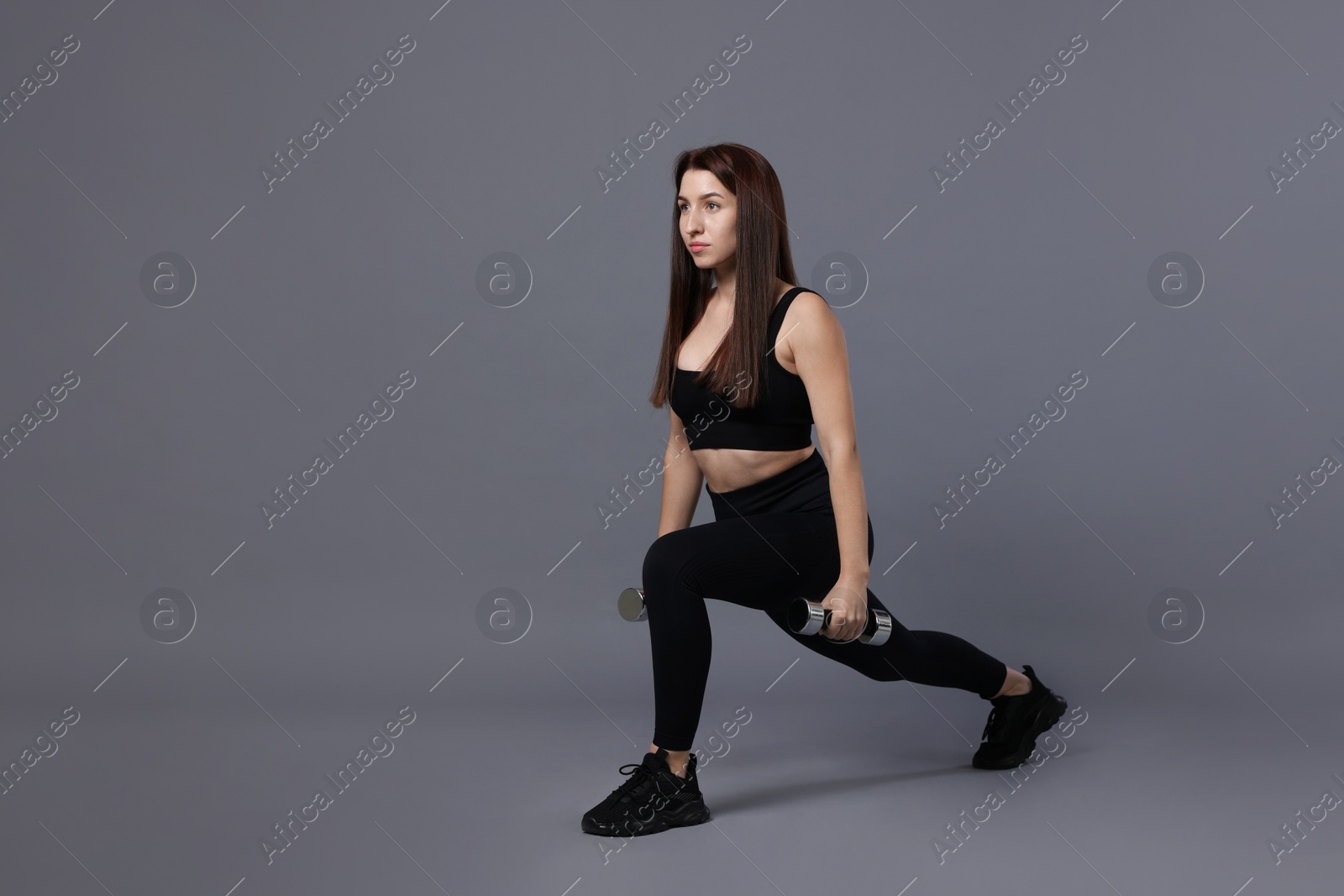 Photo of Woman in sportswear exercising with dumbbells on grey background, space for text