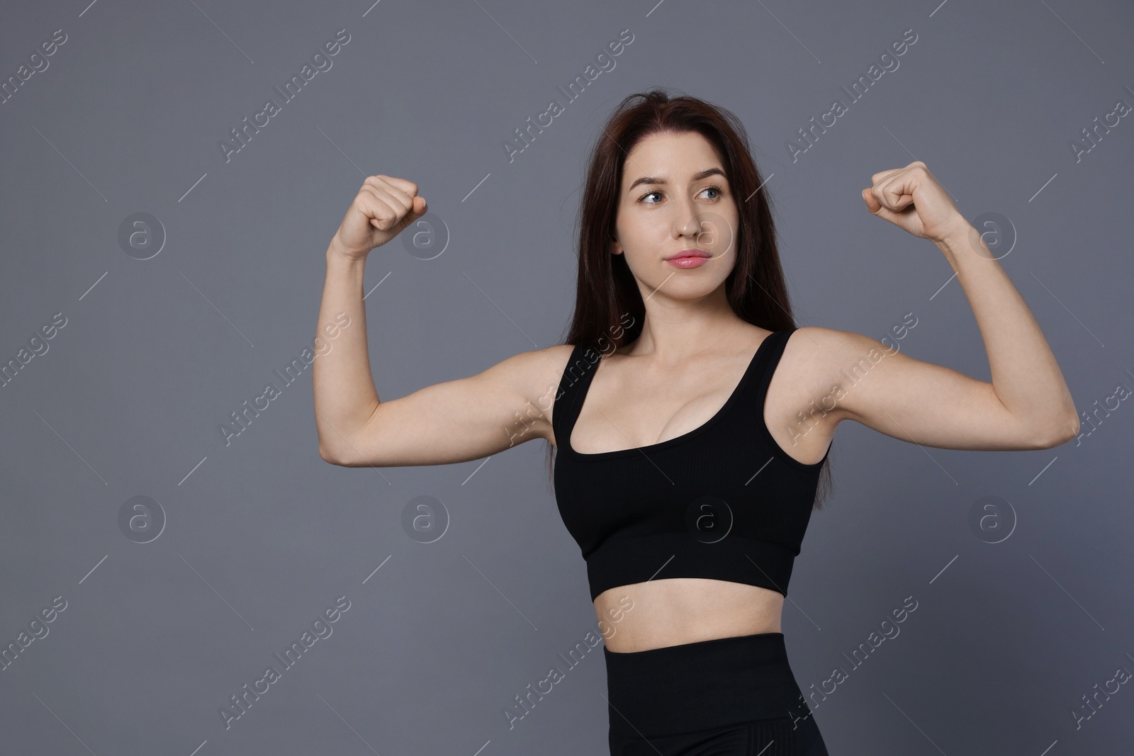 Photo of Woman in sportswear showing her biceps on grey background, space for text