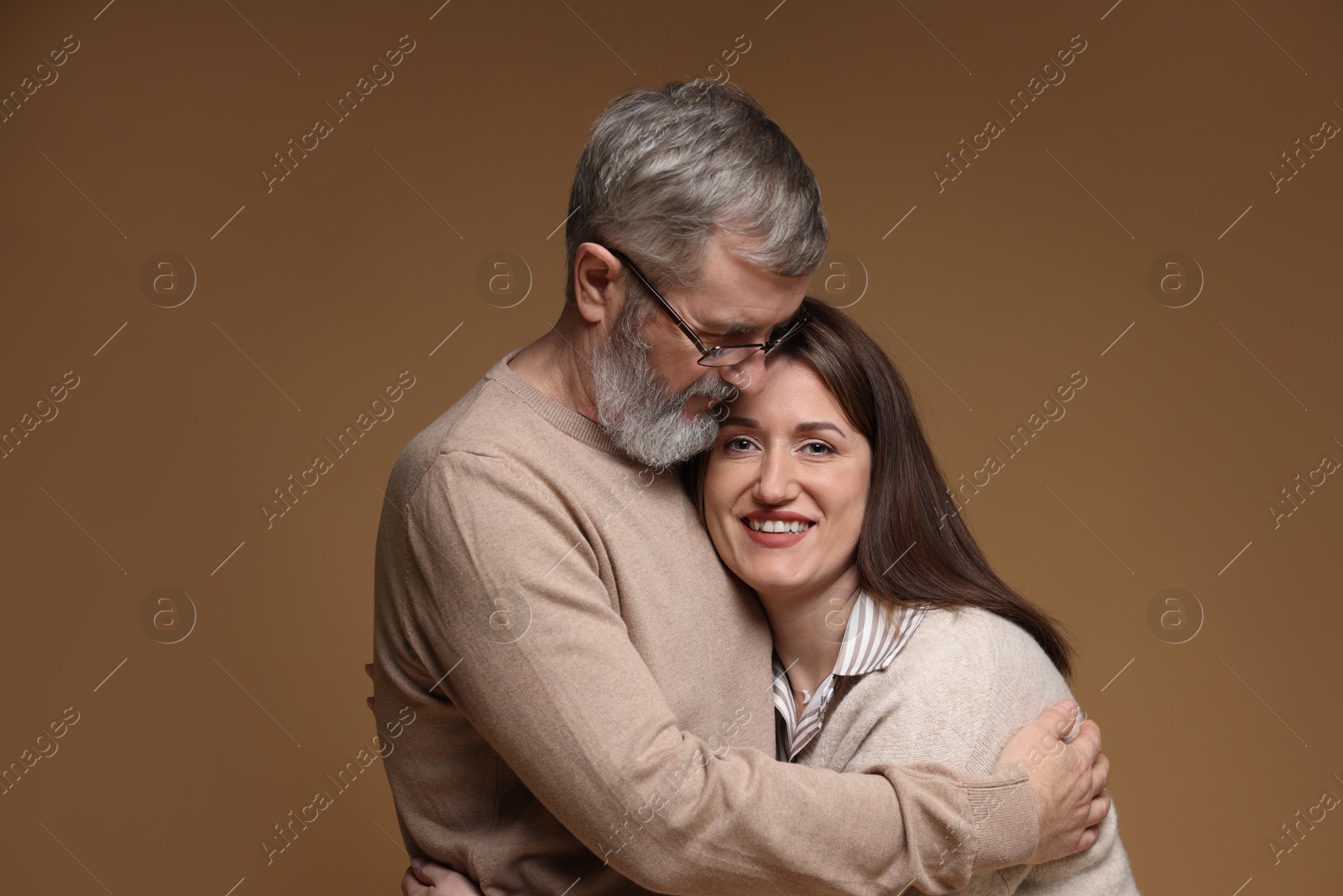 Photo of Father hugging his happy daughter on brown background