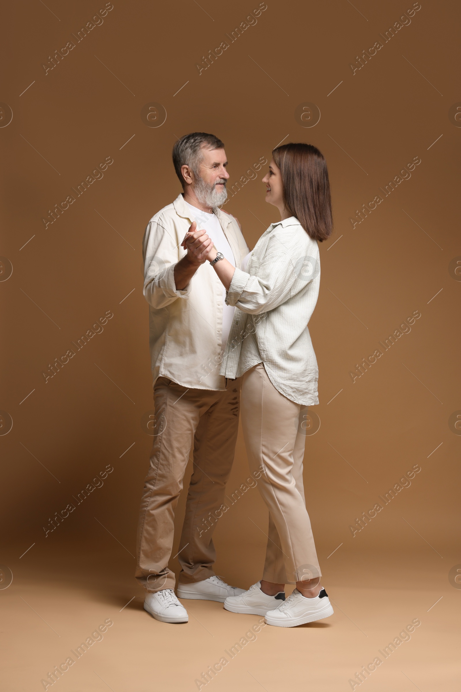 Photo of Father dancing with his daughter on brown background