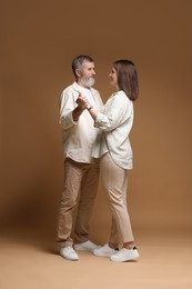 Photo of Father dancing with his daughter on brown background