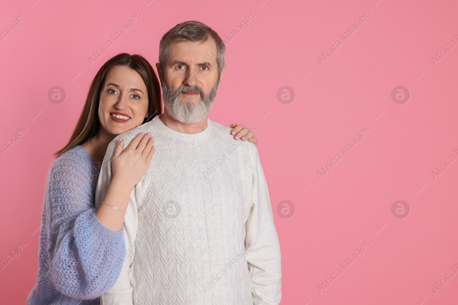 Photo of Family portrait of happy daughter and her father on pink background, space for text