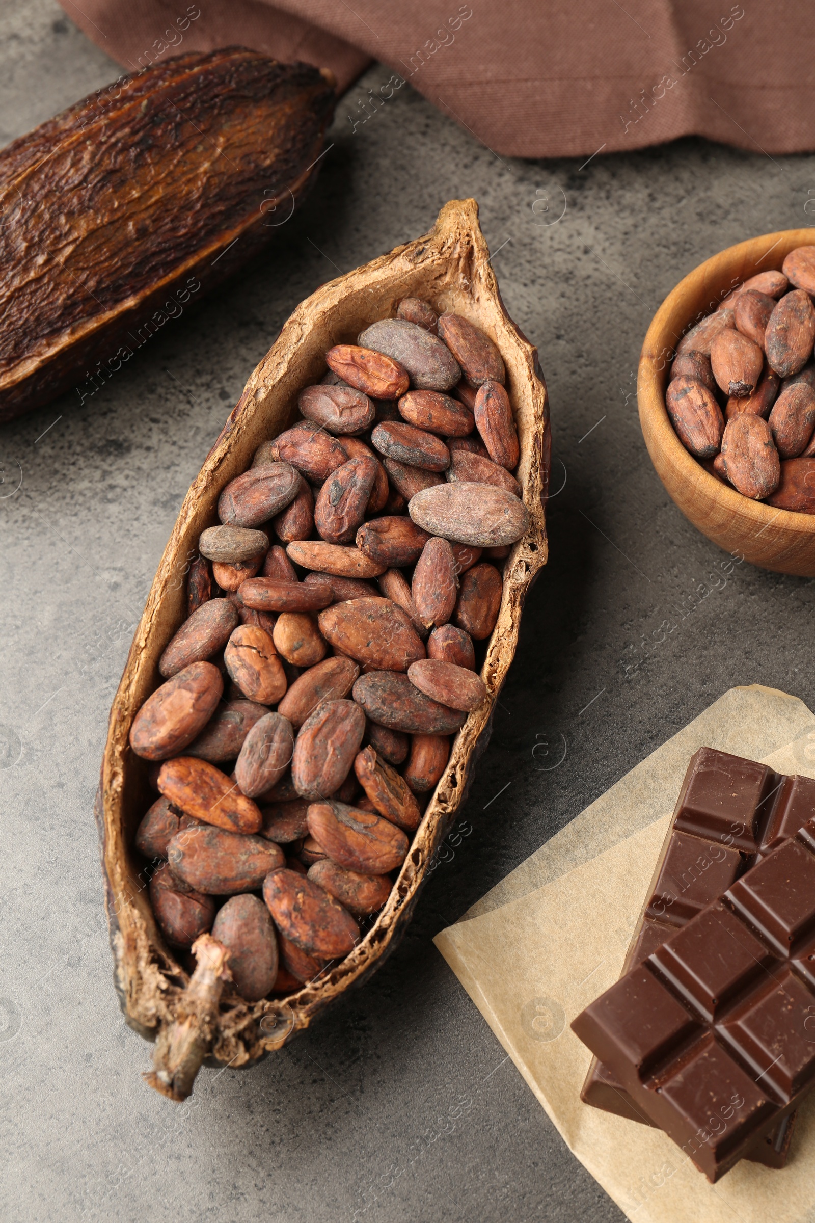 Photo of Cocoa pods with beans and chocolate on grey background