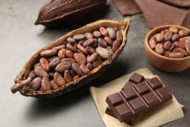 Photo of Cocoa pods with beans and chocolate on grey background, closeup