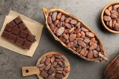 Cocoa pod with beans and chocolate on grey background, flat lay