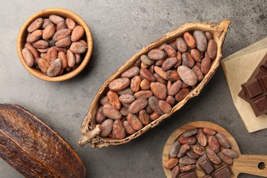 Cocoa pods with beans and chocolate on grey background, flat lay