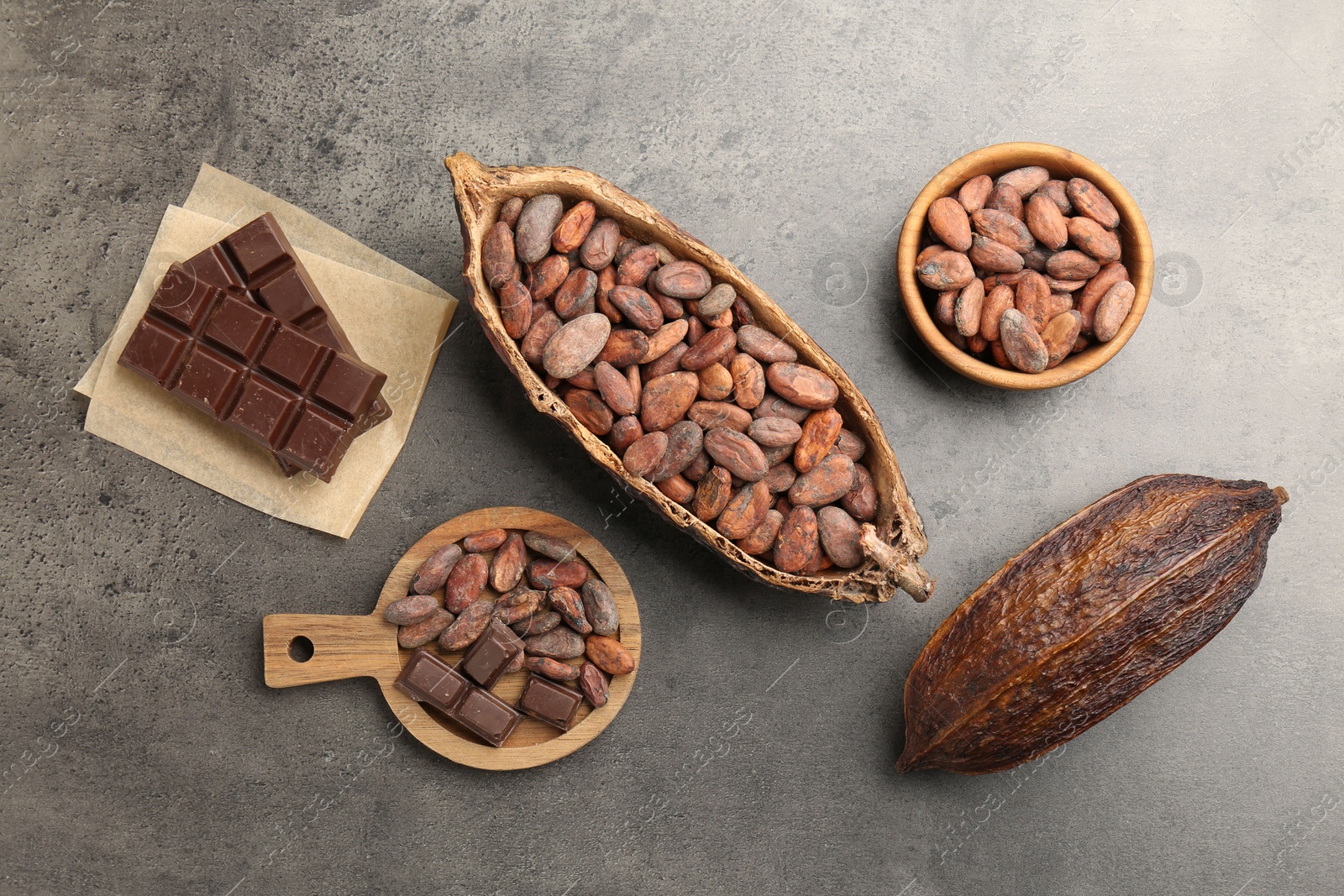 Photo of Cocoa pods with beans and chocolate on grey background, flat lay