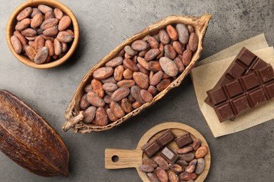 Cocoa pods with beans and chocolate on grey background, flat lay