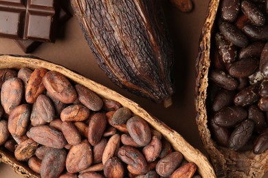 Cocoa pods with beans and chocolate on brown background, flat lay