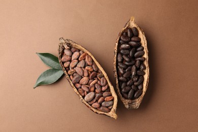 Photo of Cocoa pods with beans and leaves on brown background, flat lay