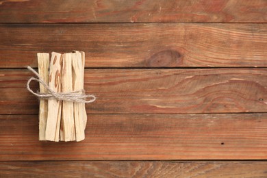 Photo of Bunch of palo santo sticks on wooden table, top view. Space for text