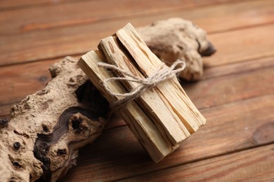 Photo of Bunch of palo santo sticks and snag on wooden table, closeup