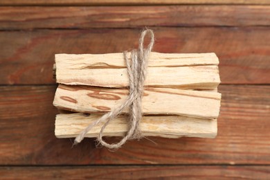 Photo of Bunch of palo santo sticks on wooden table, top view