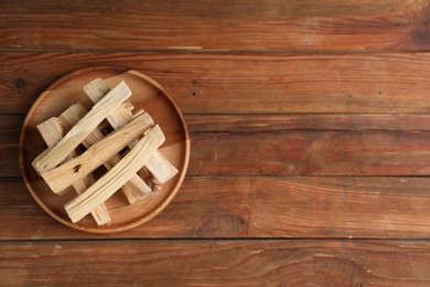 Photo of Palo santo sticks on wooden table, top view. Space for text