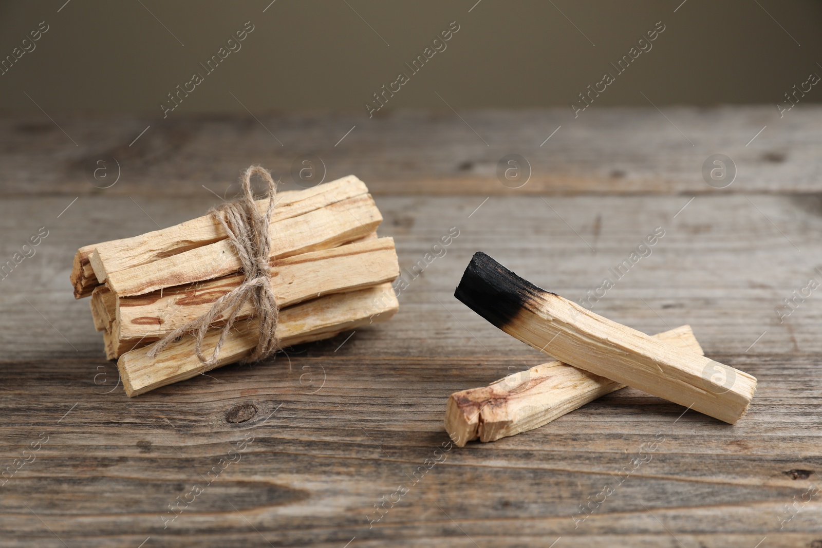 Photo of Palo santo sticks on wooden table against grey background, closeup