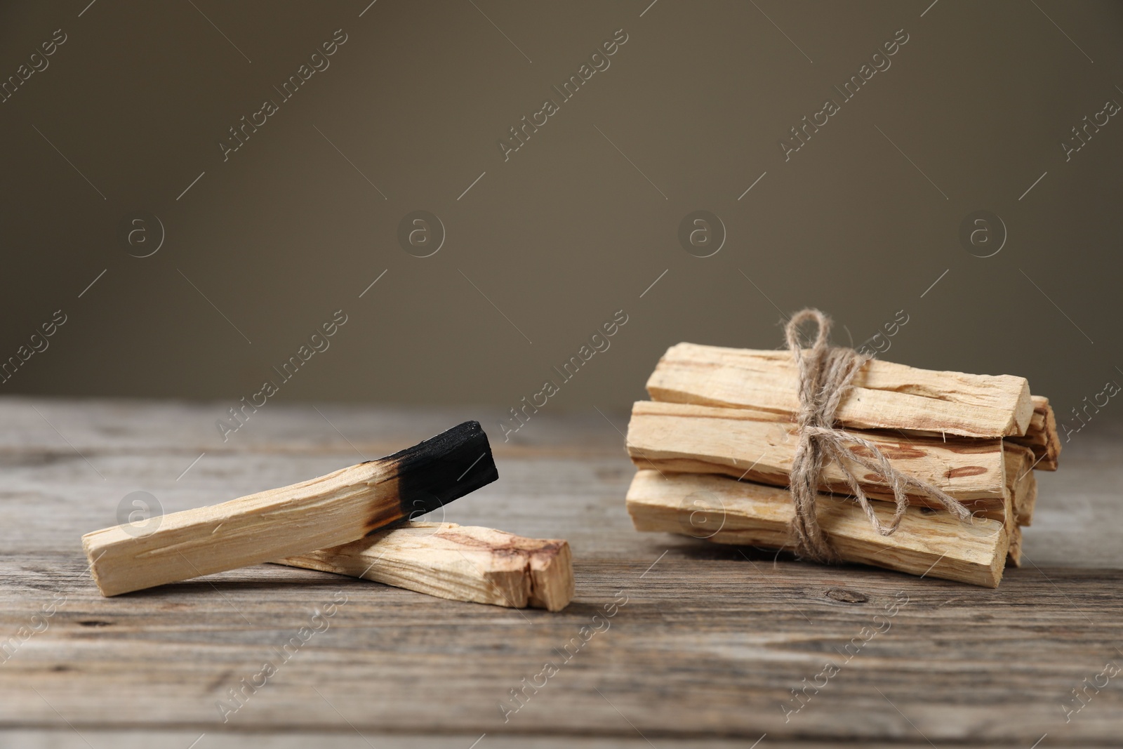 Photo of Palo santo sticks on wooden table against grey background, closeup