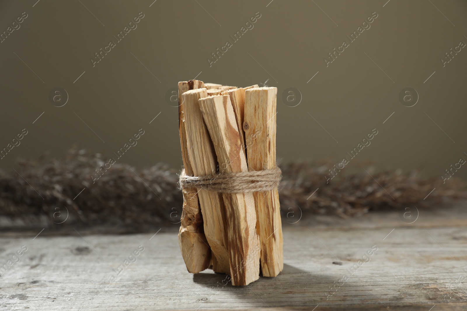 Photo of Bunch of palo santo sticks on wooden table against grey background, closeup