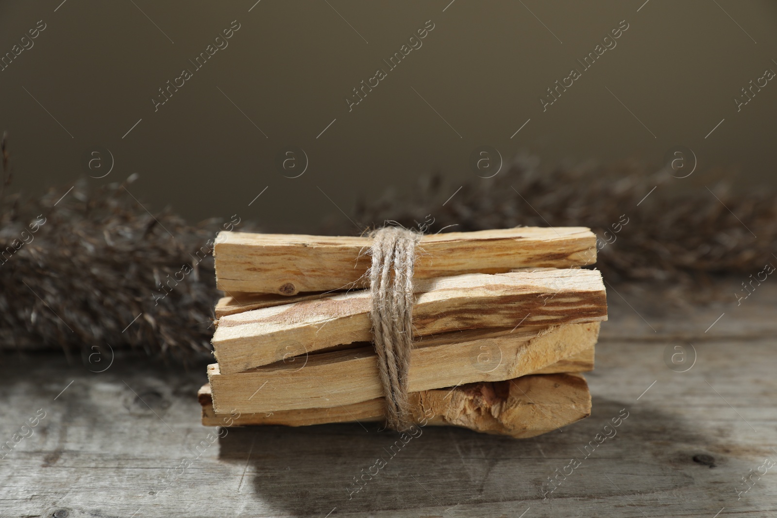 Photo of Bunch of palo santo sticks on wooden table against grey background, closeup