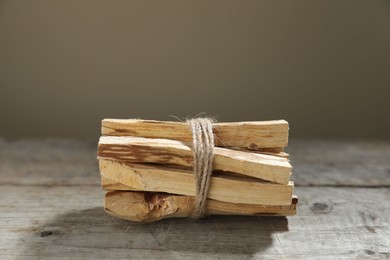 Photo of Bunch of palo santo sticks on wooden table against grey background, closeup