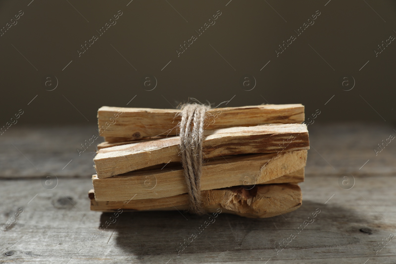 Photo of Bunch of palo santo sticks on wooden table against grey background, closeup