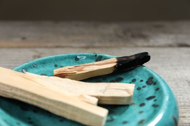 Photo of Palo santo sticks and burnt one on wooden table, closeup