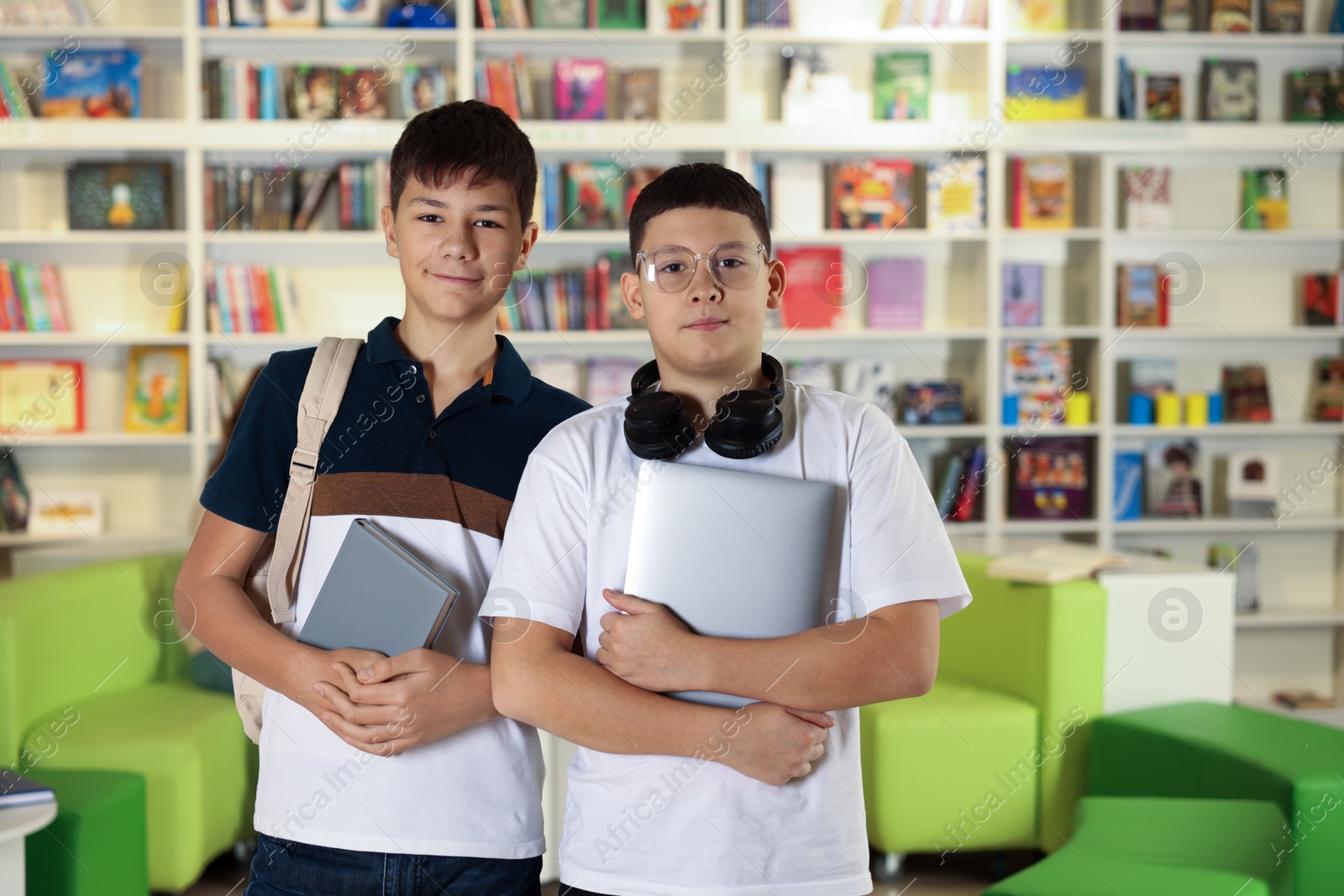 Photo of Teenage friends with laptop and book in public library