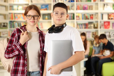 Photo of Teenage friends with laptop in public library