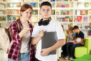 Photo of Teenage friends with laptop in public library