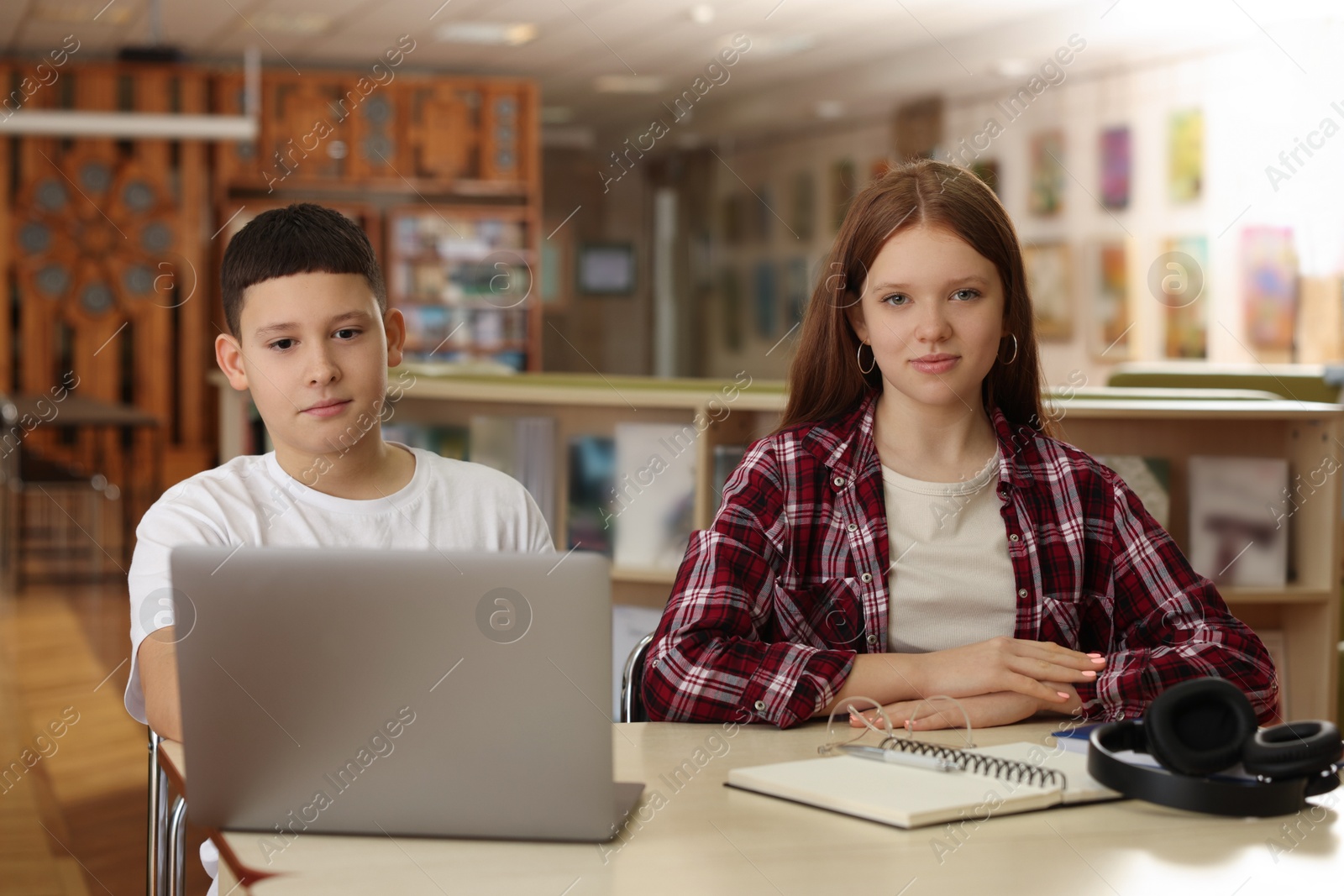 Photo of Teenage friends with laptop at desk in library