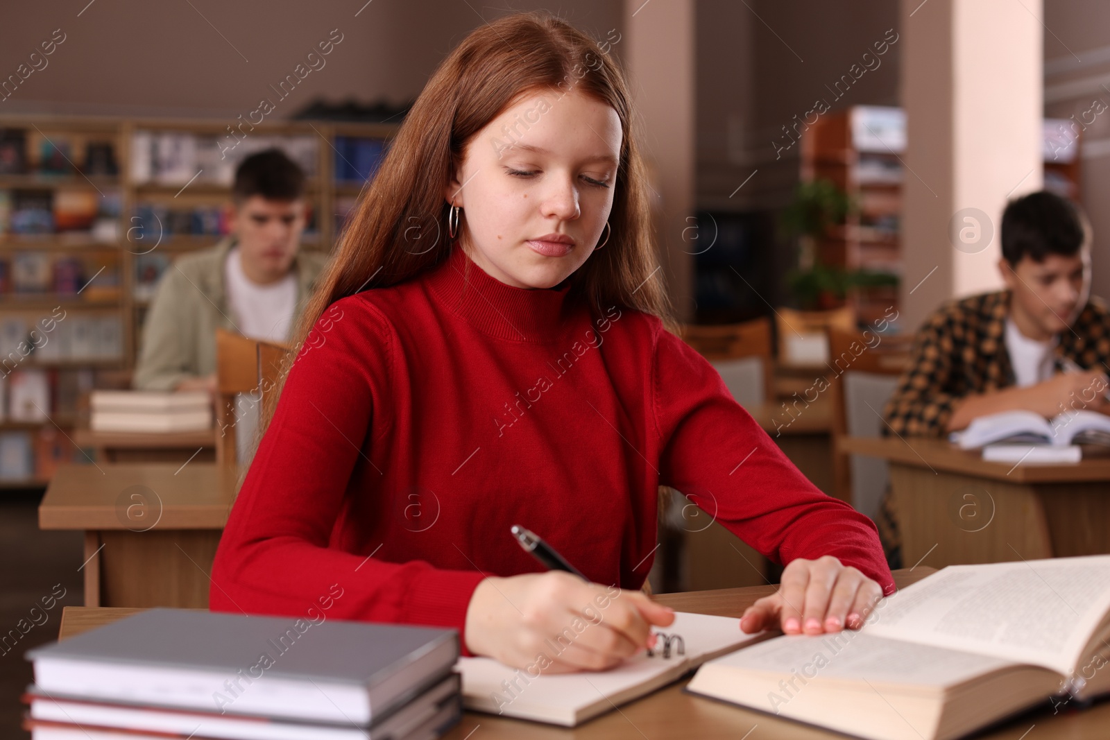 Photo of Girl taking notes at desk in public library