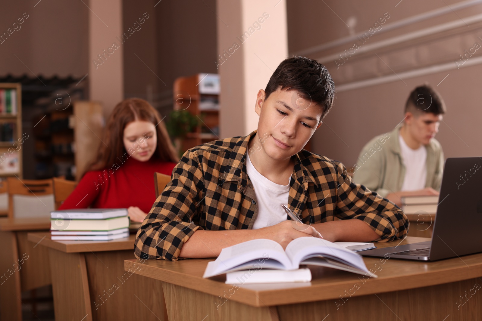 Photo of Boy taking notes at desk in public library