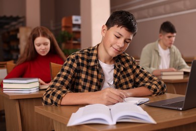 Photo of Boy taking notes at desk in public library