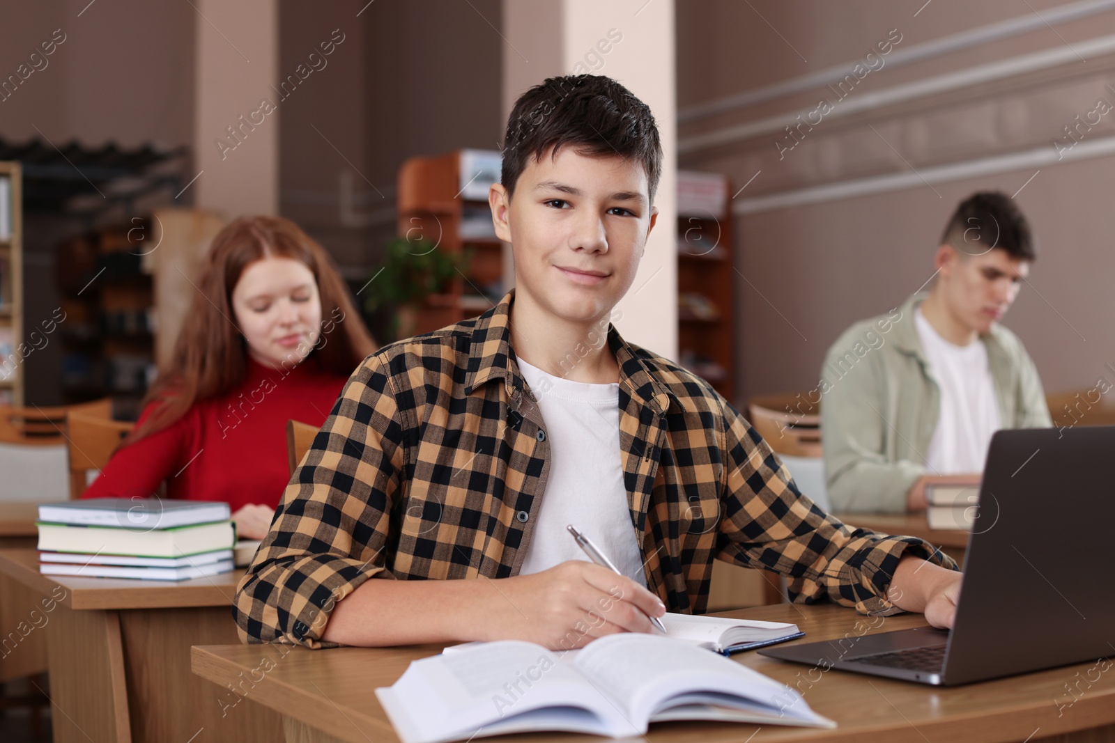 Photo of Boy taking notes at desk in public library