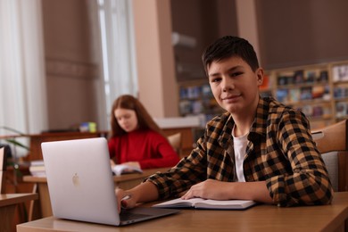 Photo of Boy using laptop at desk in public library