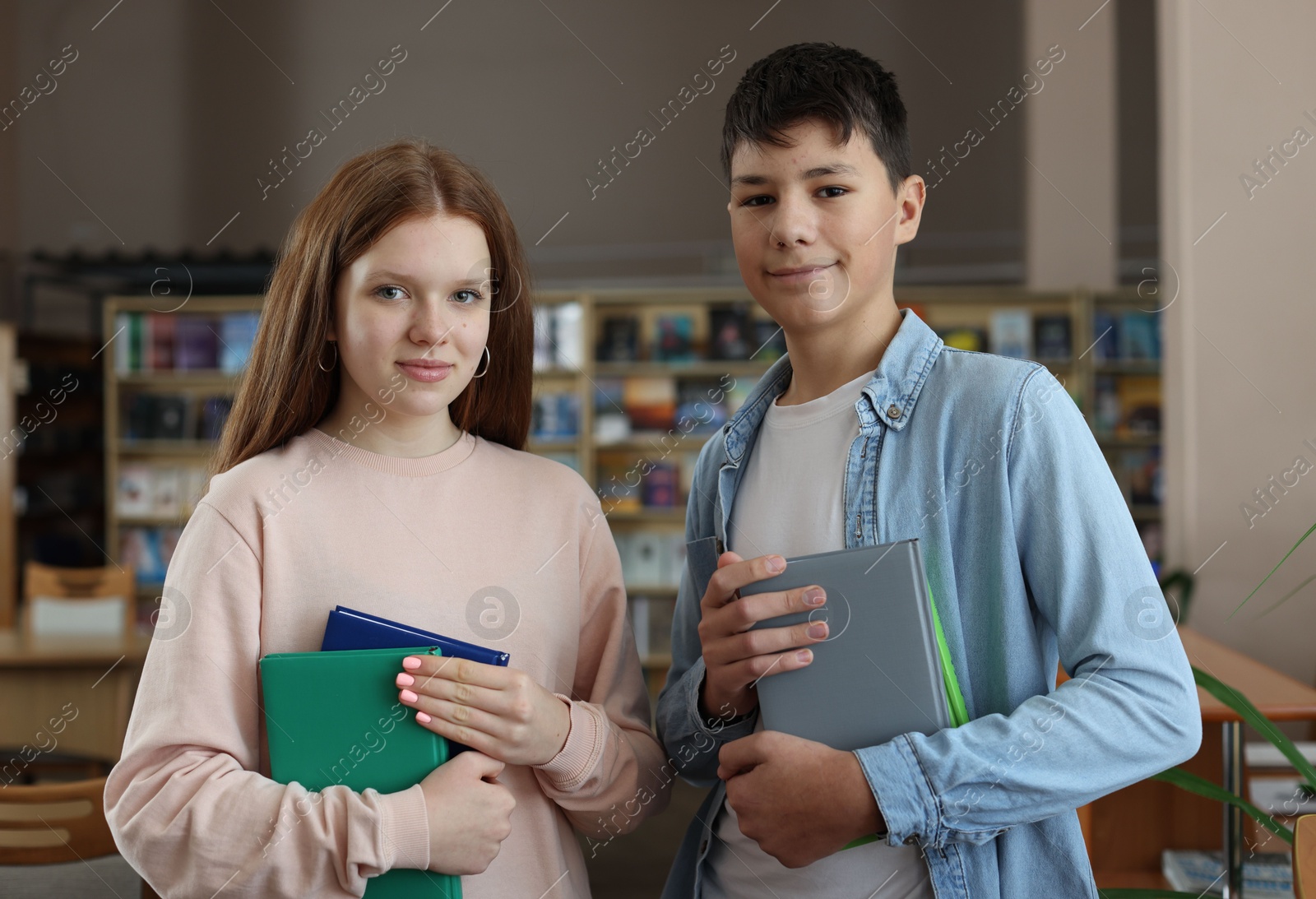 Photo of Girl and boy with books in public library