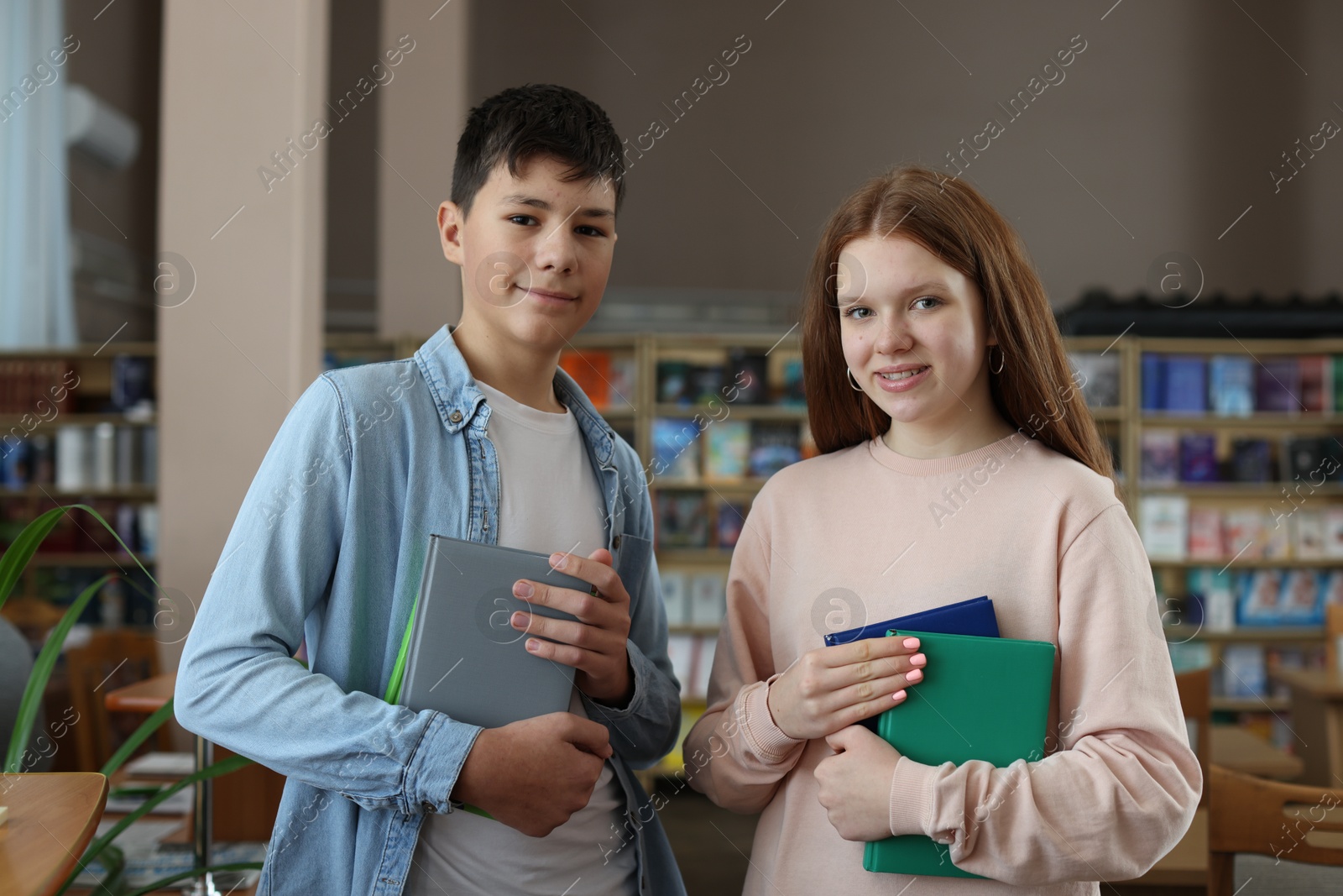 Photo of Girl and boy with books in public library