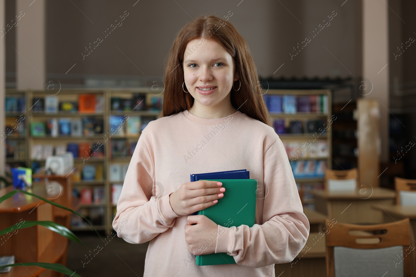 Photo of Beautiful girl with books in public library