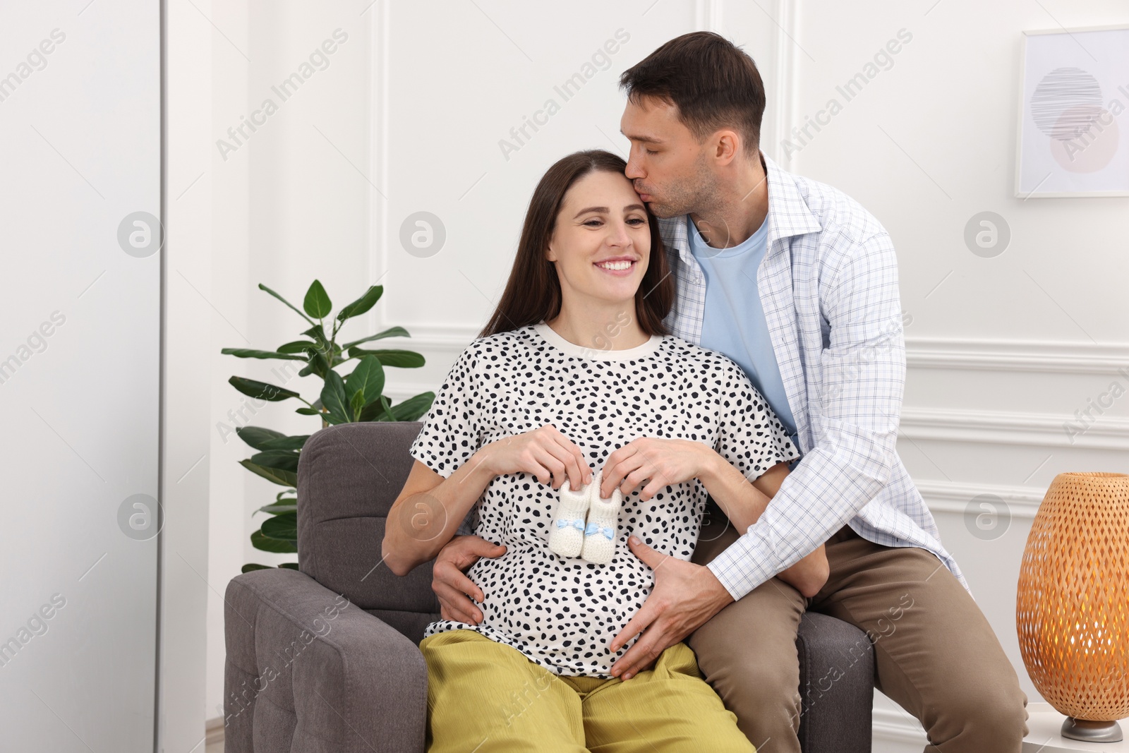 Photo of Pregnant woman and her husband with baby booties at home