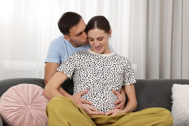 Photo of Pregnant woman and her husband on sofa at home