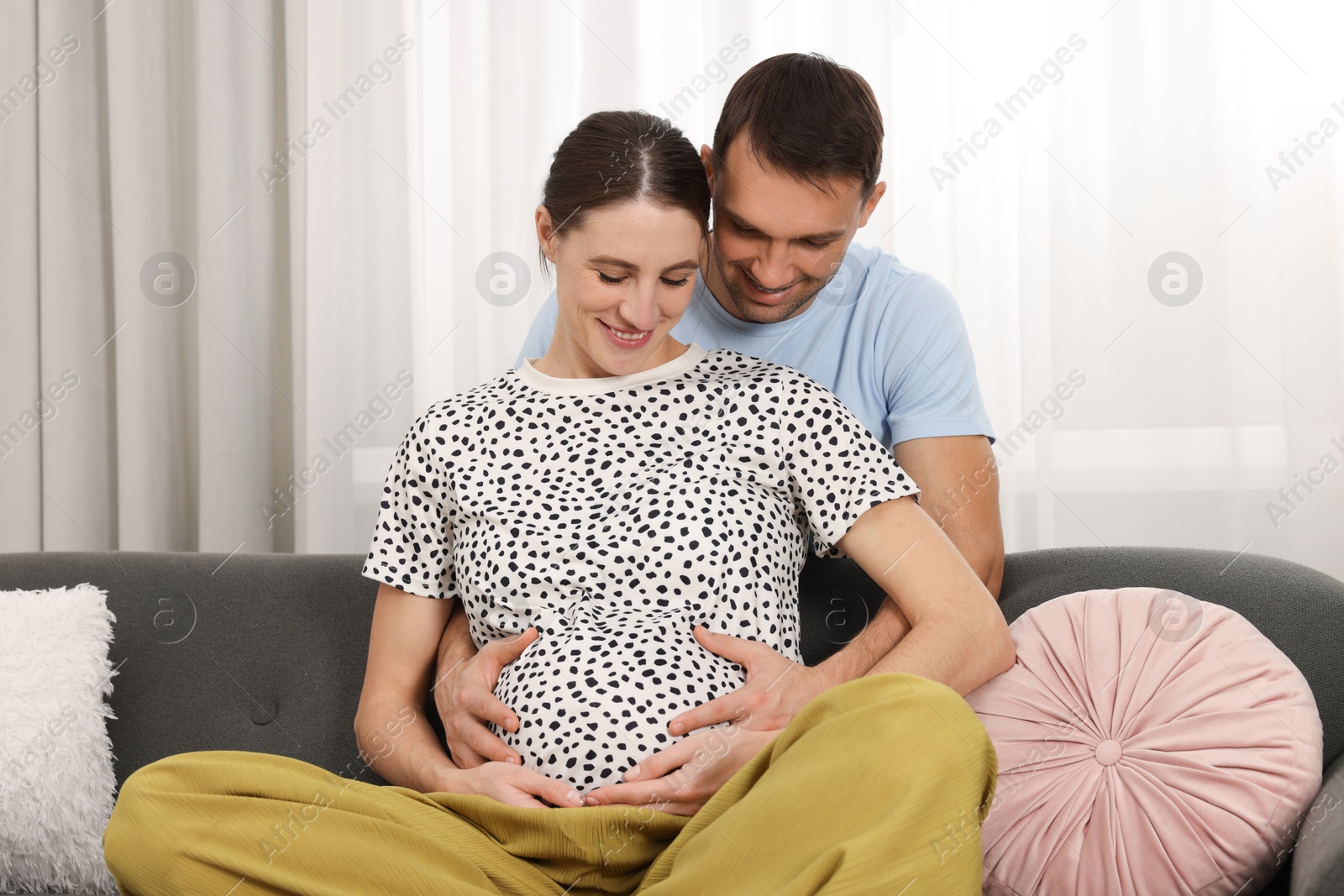 Photo of Pregnant woman and her husband on sofa at home