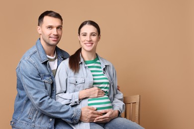 Photo of Pregnant woman and her husband on beige background. Space for text