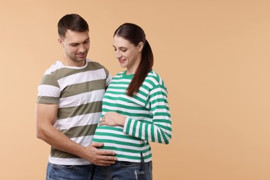 Photo of Pregnant woman and her husband on beige background. Space for text