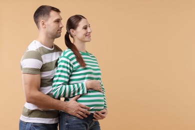 Photo of Pregnant woman and her husband on beige background. Space for text