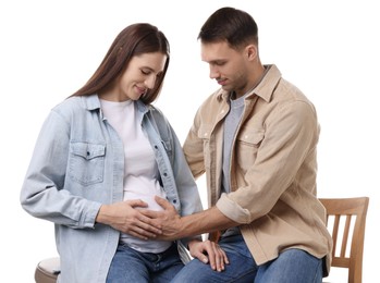 Photo of Man trying to feel baby kicks in his pregnant wife's belly on white background