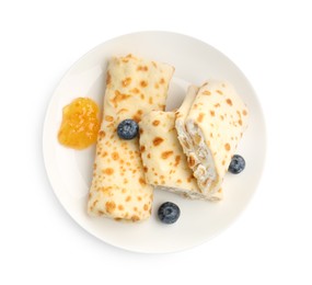 Photo of Delicious crepes with cottage cheese, jam and blueberries isolated on white, top view